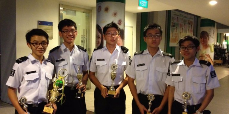 ACS(I) St John's Brigade members pose with trophies after winning awards at a brigade competition or event.